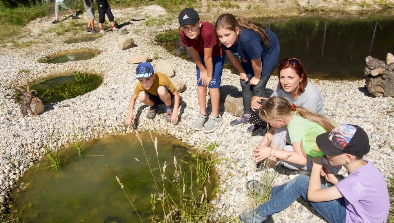 Kindergruppe untersucht gemeinsam die Flachwasserzonen am Teich